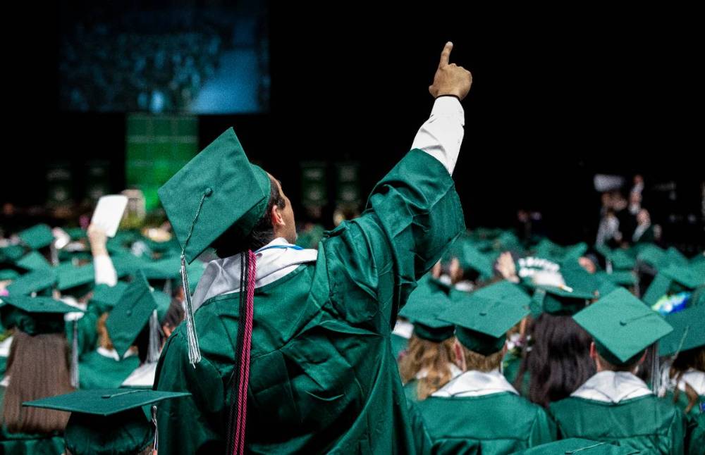 学生 pointing towards the ceiling during a graduation ceremony