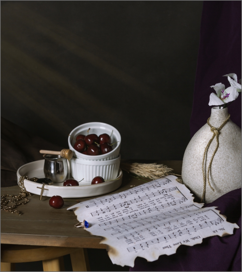 A still life with cherries, a music sheet, and a rustic vase on a wooden table
