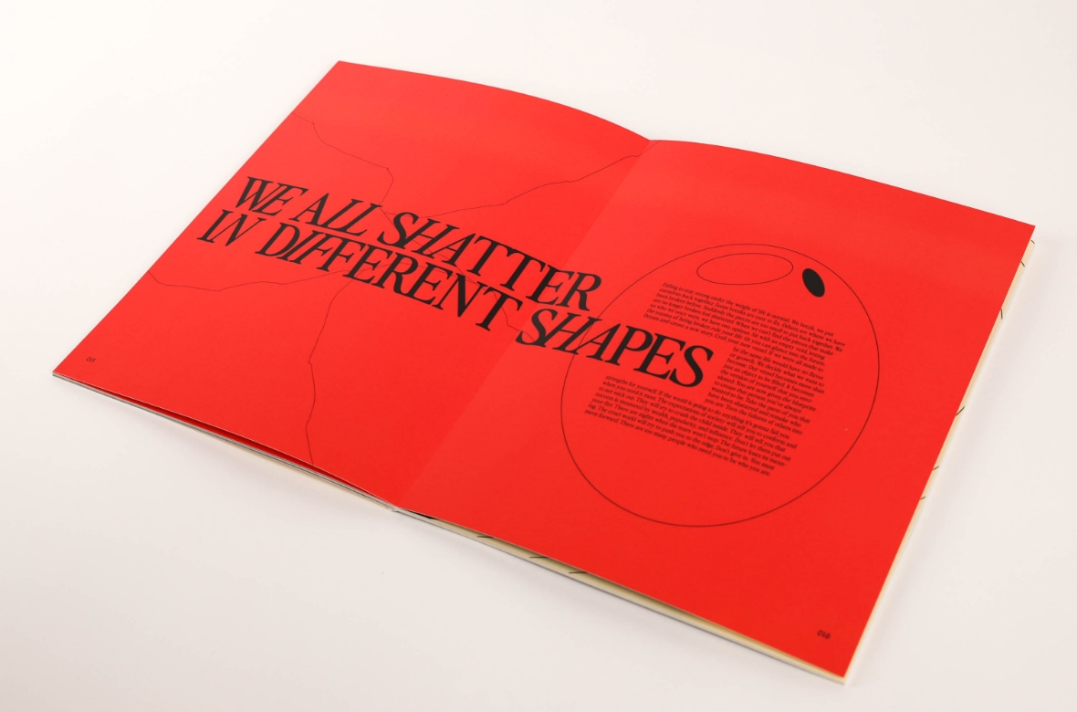 Open magazine with red pages and bold black text stating "We all shatter in different shapes" 