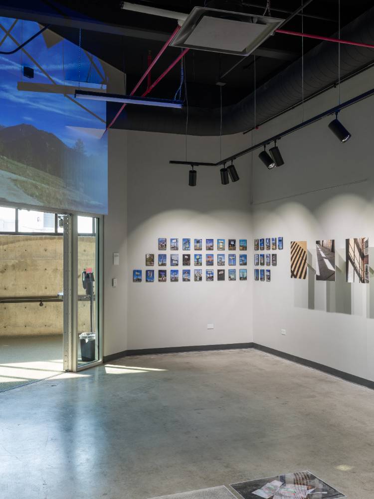 Modern gllaery with photographs and abstract art on walls, concerte floor, and exposed ceiling features. 