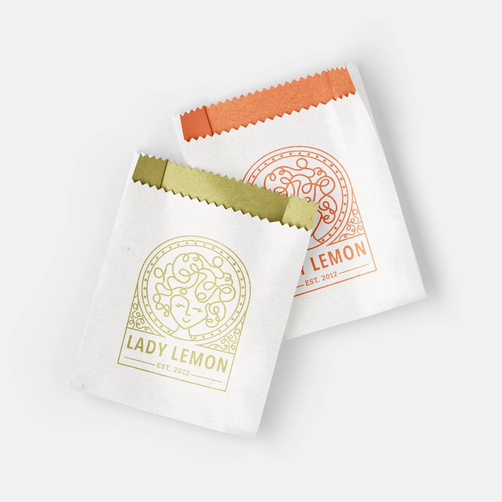 Two decorative white paper packets with colorful tops and Lady Lemon branding.              