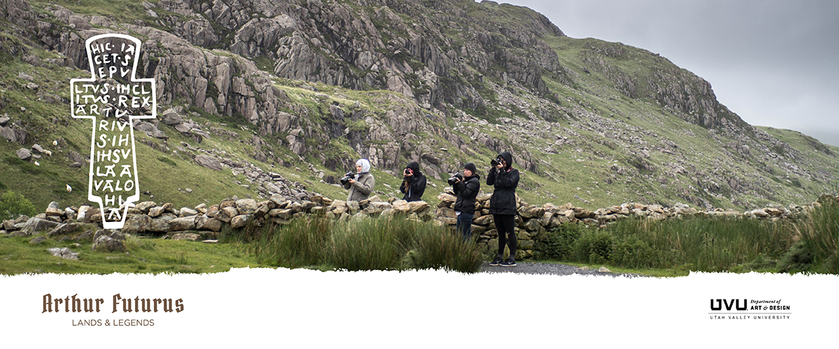Group of photographers on a grassy hill with a stone wall, rocky hills in the background, and 犹他谷大学 logo.              