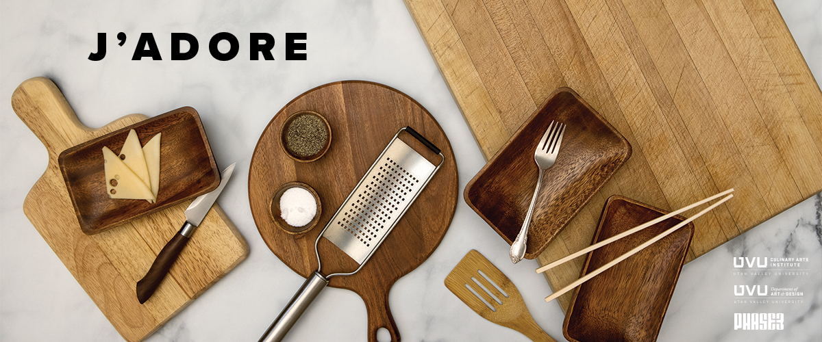 Kitchen utensils and boards arranged on a marble surface, with cheese, grater, and utensils.              