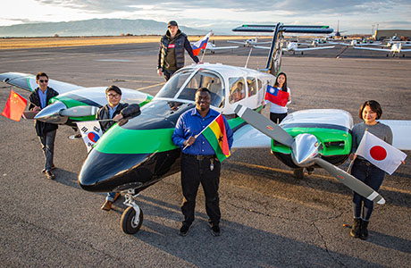 students holding flags around a plane