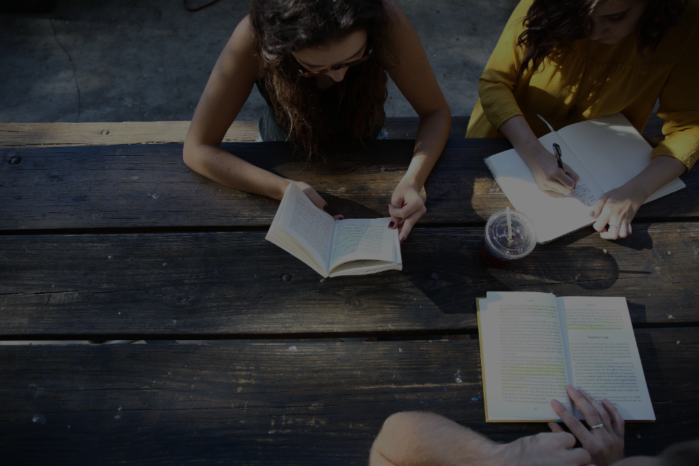 学生s reading a book on a table outdoors