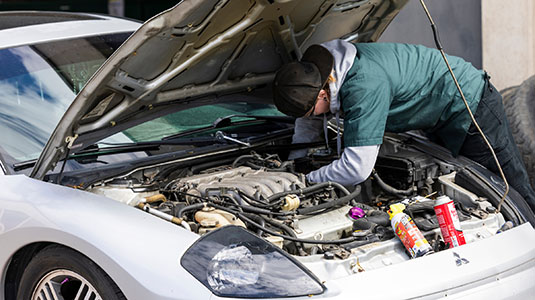 student working on a car engine