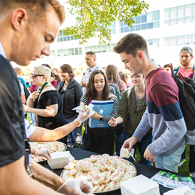 学生s gathered in a crowd around a table covered with cookies