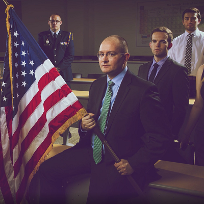 man holding an american flag with other men behind him.
