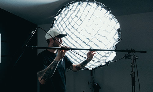 person setting up a boom mic behind a large flood light