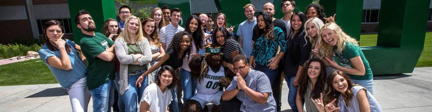 A large group of students standing in front of UVU logo structure.