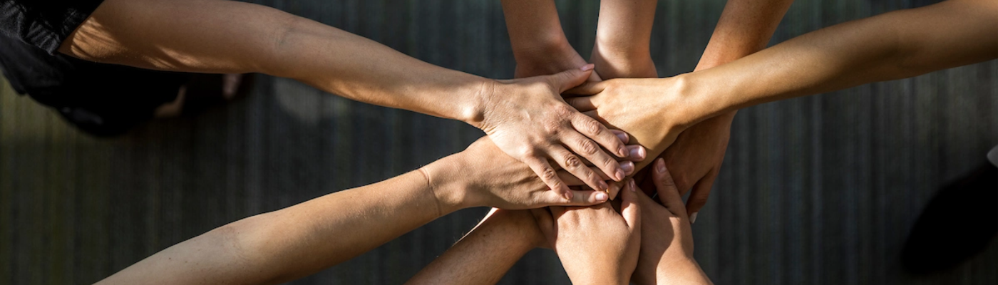 Nine outstretched hands stacked in an "all in" gesture.