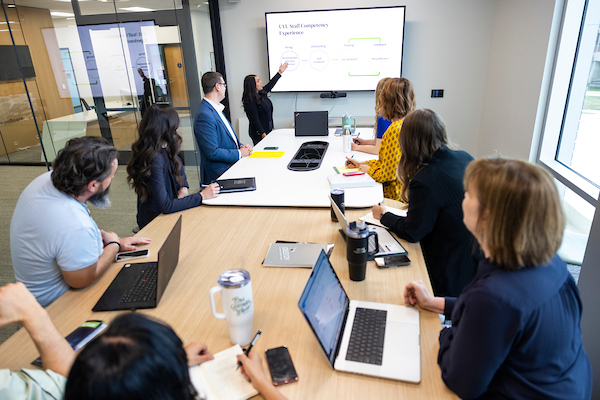 People in a meeting room with laptops looking at a presentation