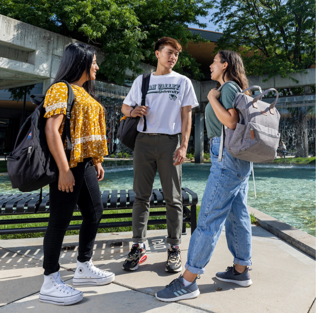 Three students standing together in conversation.