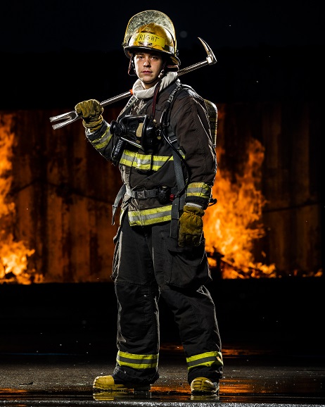 Firefighter with pike pole standing in front of blazing fire