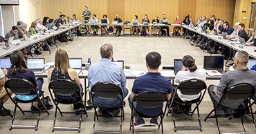 Photo of a 教师参议院 meeting. A large room with tables set in a square with the senate facing inwards towards eachother.