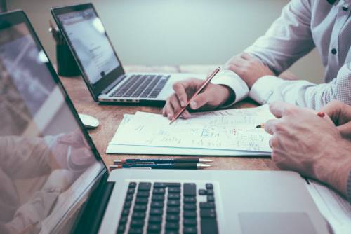 Hands of two individuals working on paperwork