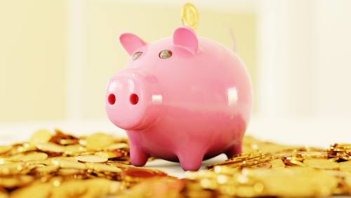 Piggy bank standing on a pile of gold coins