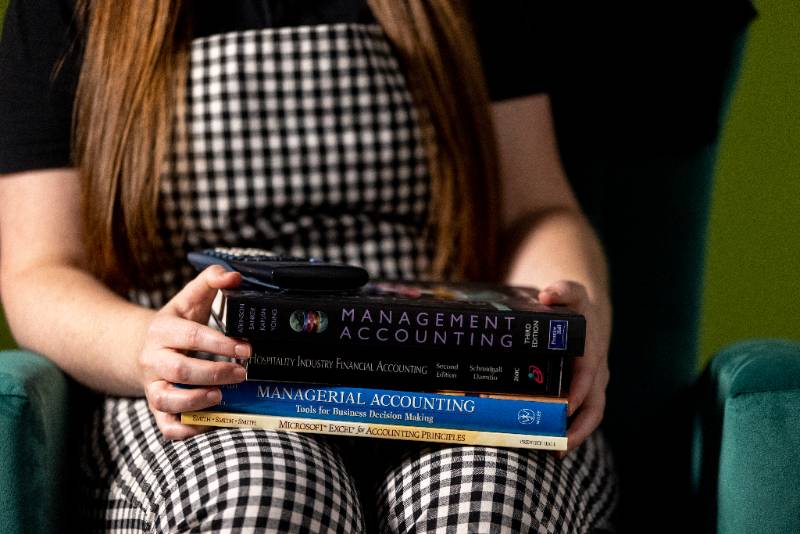 student sitting down holding accounting books in thier lap