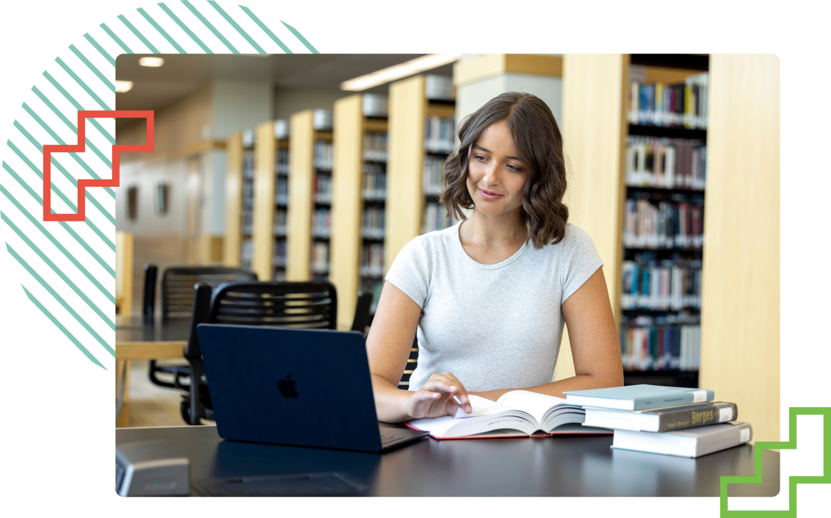 学生 looking at their laptop while seated at a desk in the Fulton Library at UVU