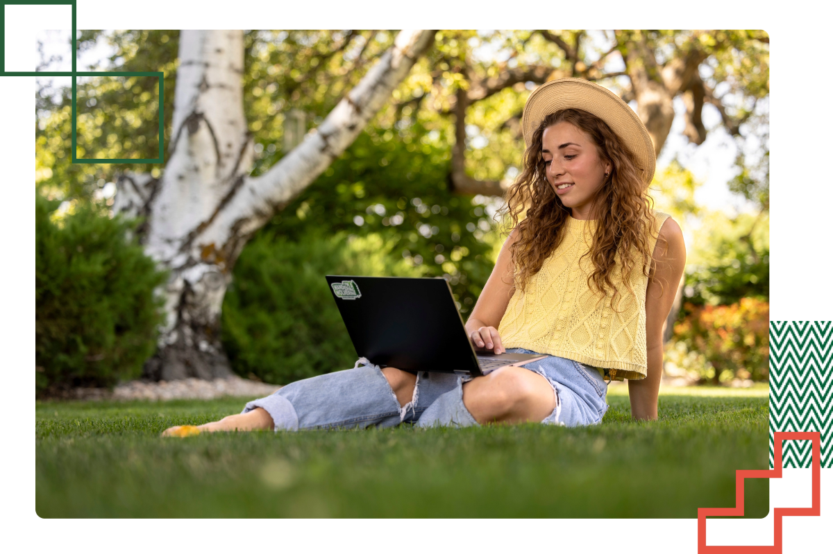 student laying on a blanket outdo或s with a laptop in front of them