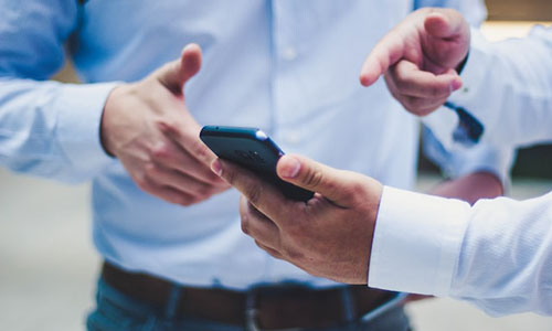 Two people pointing at a phone