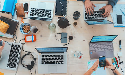 People sitting at a table with laptops and technology