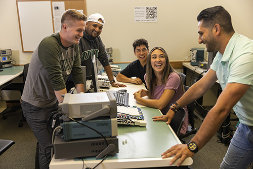 学生s gathered around a table with electronic equipment on the table