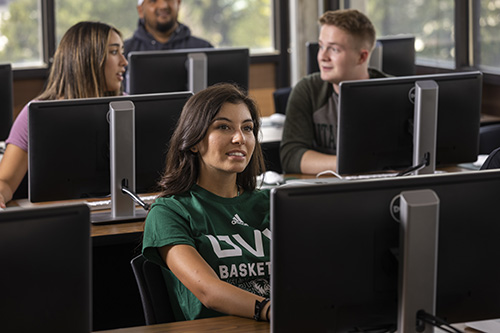 学生s behind individual computers sitting in a class