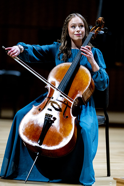 学生 in blue dress plays the cello.