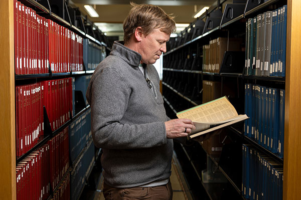 a shot of a person in the UVU library reading a book between the shelves