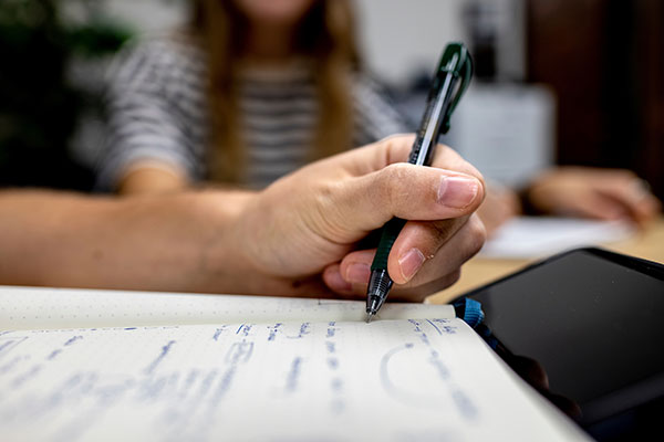 A person holding a pen to paper