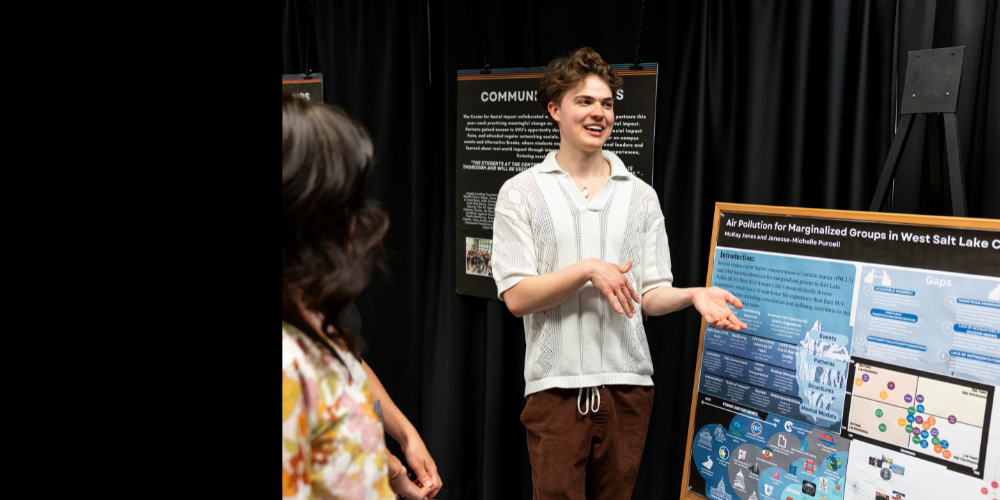 学生 smiling while presenting poster with research data