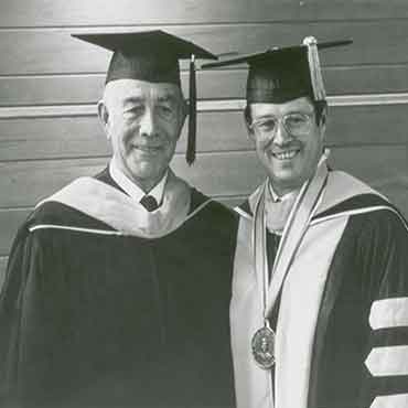 威尔逊索伦森 standing with J. Marvin Higbee, both are wearing graduation regalia.